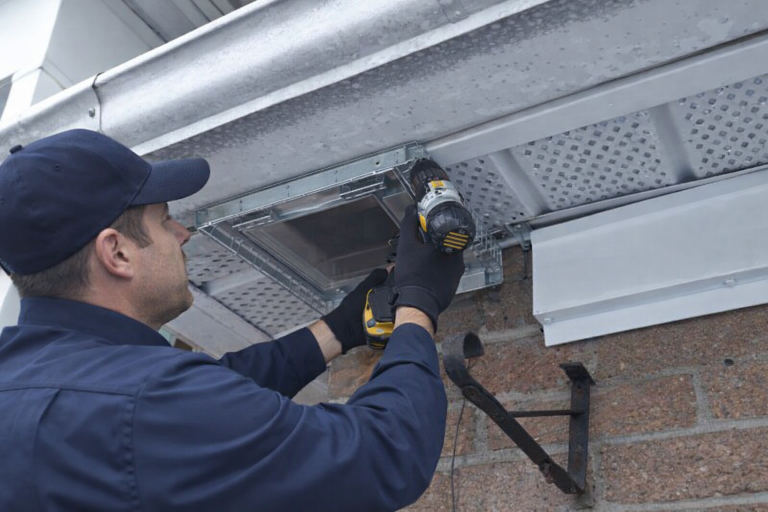 A wildlife technician installs a one way door over a damaged soffit.